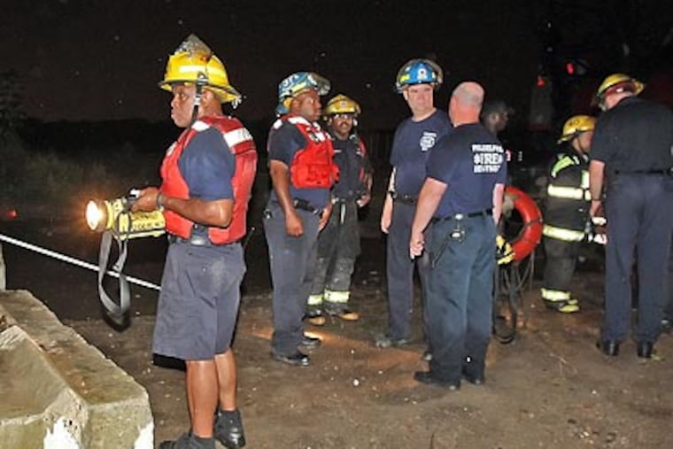 Philadelphia firefighters scan the Schuylkill River near 56th Street. (Steven M. Falk/Staff Photographer)