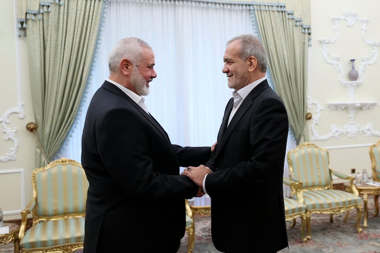In this photo released by the Iranian Presidency Office, President Masoud Pezeshkian, right, shakes hands with Hamas chief Ismail Haniyeh at the start of their meeting at the President's office in Tehran, Iran, on Tuesday, July 30, 2024.