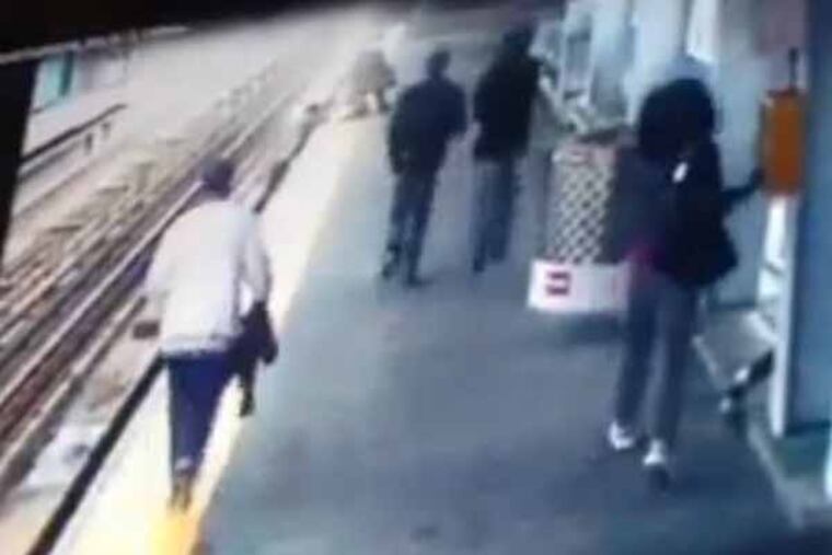 Video grab of baby in stroller that rolled off platform into SEPTA train tracks. Video shows mother on edge about to jump down. Notice woman on right hitting the emergency call button before proceeding to give assistance.