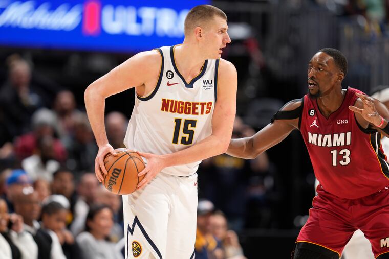 Denver Nuggets center Nikola Jokic, left, looks to pass the ball as Miami Heat center Bam Adebayo defends in the first half of an NBA basketball game Friday, Dec. 30, 2022, in Denver. (AP Photo/David Zalubowski)
