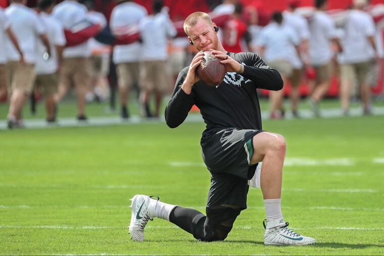 Eagle quarterback Carson Wentz, center, stretches during warmups as a group rehearses unfurling the American Flag on the filed of Raymond James Stadium on Sunday September 16, 2018. MICHAEL BRYANT / Staff Photographer