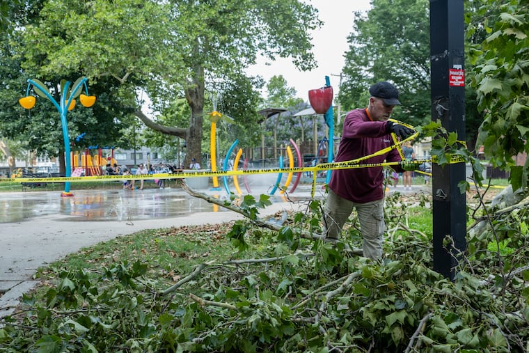 A Philadelphia Parks and Recreation worker ties caution tape near where tree branches have fallen from Saturday’s storm at Wharton Square Playground in Point Breeze, Philadelphia on Monday, July 13, 2026.
