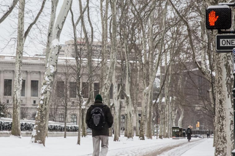 A pedestrian walks along a snow covered pathway on Ben Franklin Parkway on Monday, March 17, 2014 after a few inches of snow fell on the city. (Colin Kerrigan / Philly.com)