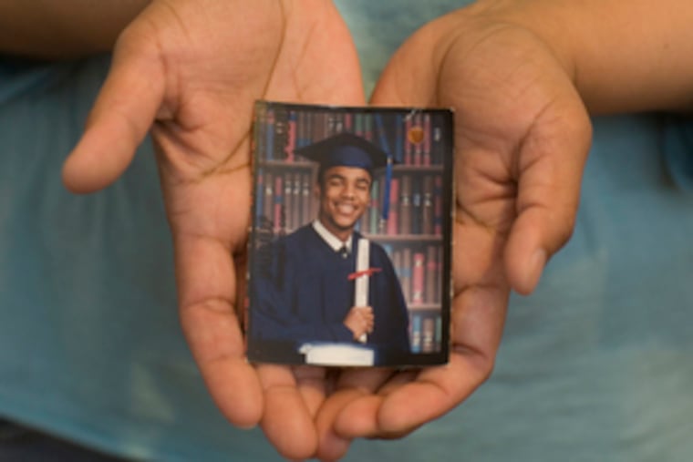 Adrienne Kaplan cradles a photo of her son, Theodore Thomas Jr., who died after being hit by a car in Center City. Thomas' family is trying to make sense of the tragedy.