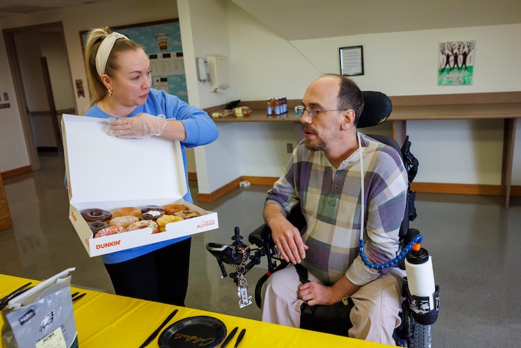 At right is Aaron Deede a resident of Inglis House. He is starting to take classes at Community College of Philadelphia. At left, Jaclyn Monaco, director of Therapeutic Life Enrichment, offers treats during the celebration for students.