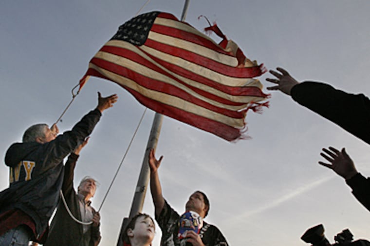 (Left-Right) Navy veteran Dan Rodgers of Horsham, Pa, Marvin Hume, 87, Jonathan Teiper, 6, of Mullica Hill and Dan Check of Villas Pull in the flag as it is lowered at Sunset Beach. (Elizabeth Robertson / Inquirer Staff)