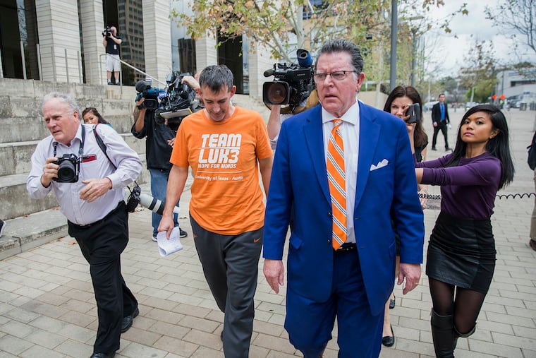 Texas men's tennis coach Michael Center, center left, walks with Defense lawyer Dan Cogdell, center right, away from the United States Federal Courthouse in Austin on Tuesday. Center is among those charged in a scheme that involved wealthy parents bribing college coaches and others to gain admissions for their children at top schools, federal prosecutors said Tuesday. (Ricardo B. Brazziell