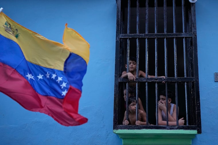Children look out at a pro-government march from a window in La Guaira, Venezuela, Tuesday, Jan. 20, 2026.