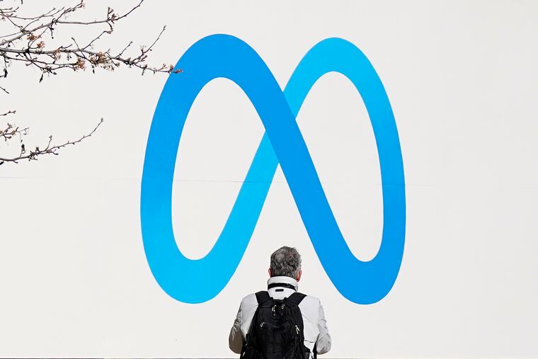 A person stands in front of a Meta sign outside of the company's headquarters in Menlo Park, Calif., in early March.