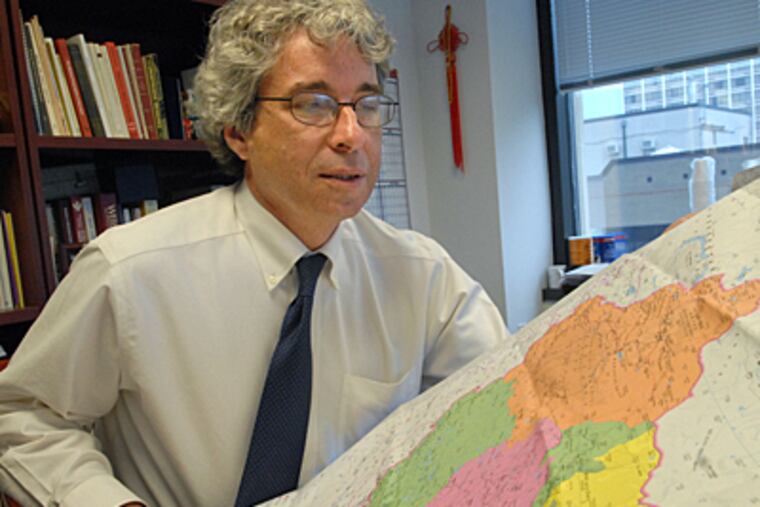 Dr. David Metzger of the University of Pennsylvania with map of China where he will spend two weeks research AIDS for a project. (Peter Tobia / Inquirer)