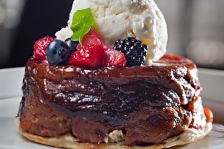 Deeply caramelized apple tarte Tatin, with berries, vanilla ice cream, and orange mint, is one of the bistro’s best dessert offerings. (DAVID M WARREN / Staff Photographer)