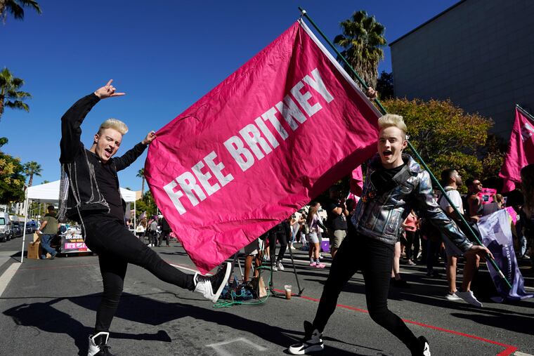 Twins Edward, right, and John Grimes of Dublin, Ireland, hold a "Free Britney" flag outside a hearing concerning the pop singer's conservatorship at the Stanley Mosk Courthouse in Los Angeles.