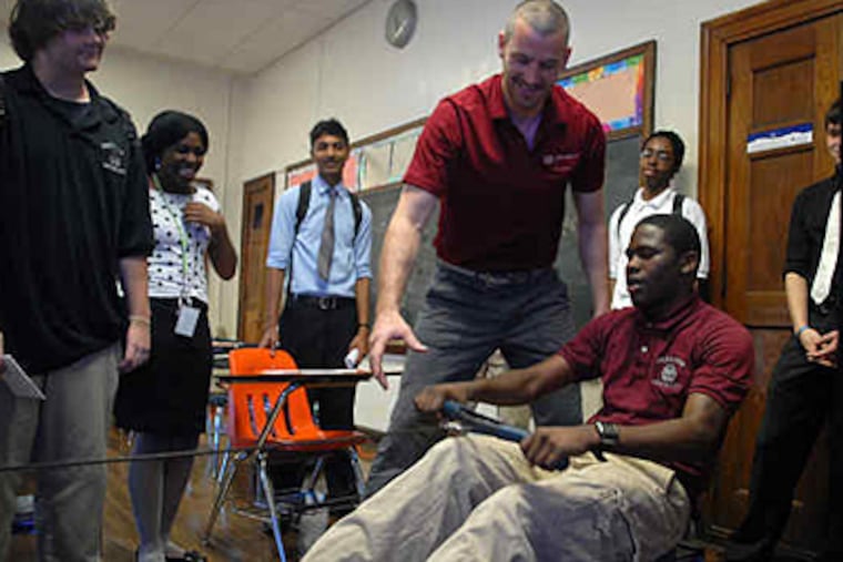 Olympic and world champion rower Dan Beery helps Parkway Center City High School sophomore Simone Mitchell with an indoor rowing machine. Mitchell was a natural, Beery said. (Tom Gralish / Staff)