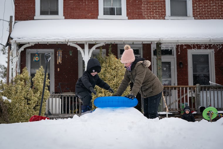 Armani Hennessey, 5, receives help from his cousin Amanda Guzik, 17, preparing to sled down a hill in the front yard in Norristown on Wednesday.