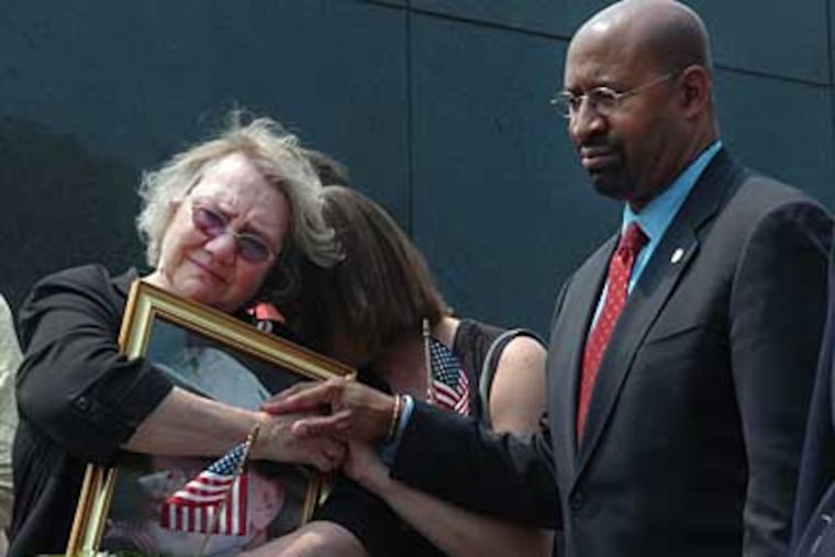 Celeste Zappala of Mt. Airy holds a photo of her son, Sgt. Sherwood Baker. She is comforted by her best friend, Jennifer Cox (center), and Mayor Michael Nutter while the inscribed names of servicemen killed in Iraq or Afghanistan are unveiled near the Korean War Memorial. (Sarah J. Glover / Staff Photographer)