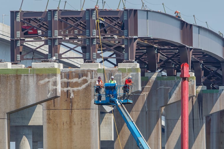 Bridge construction workers are lowered via a cherrypicker to the floating barge under the spans of the older Great Egg Harbor Bridge, which is still under construction, on August 8, 2018. MICHAEL BRYANT / Staff Photographer