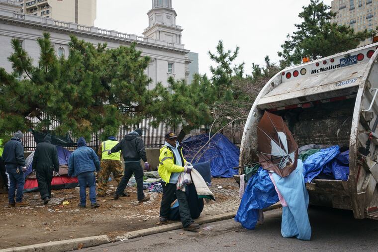 City workers clean out a tent encampment Monday where people who are homeless had been staying at 18th and Vine Streets.