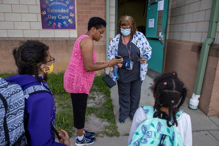 Nurse Kathy Barbieri speaks with Shandra Cruz. Shandra is showing Kathy her phone app used by Bobby's Run Elementary School in Lumberton, N.J., to okay when students can enter school during COVID-19.