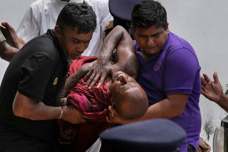 An injured Sri Lankan Buddhist monk is carried away after being among many anti-government protesters attacked by government supporters outside Prime Minister Mahinda Rajapaksa's residence in Colombo, Sri Lanka, on Monday.