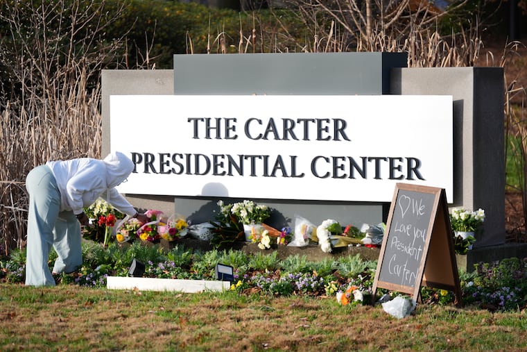Christine Mason, of Atlanta, places flowers at entrance the The Jimmy Carter Presidential Center in Atlanta.