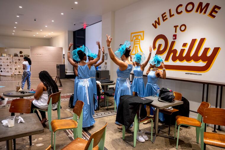 Members of the Dance4Life troupe from Claymont, Del., warm up inside the Bourse food court before their scheduled Wawa Welcome America performance in the Gospel on Independence Mall Sunday evening was canceled due to severe storms in the forecast.