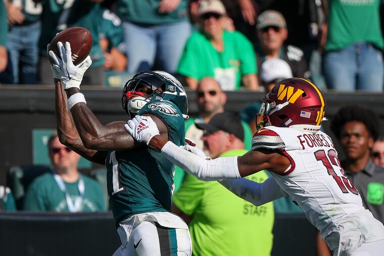 Philadelphia Eagles wide receiver A.J. Brown (left) catches a touchdown pass over Washington Commanders cornerback Emmanuel Forbes during the fourth quarter of the Birds' 34-31 overtime win over the Commanders.