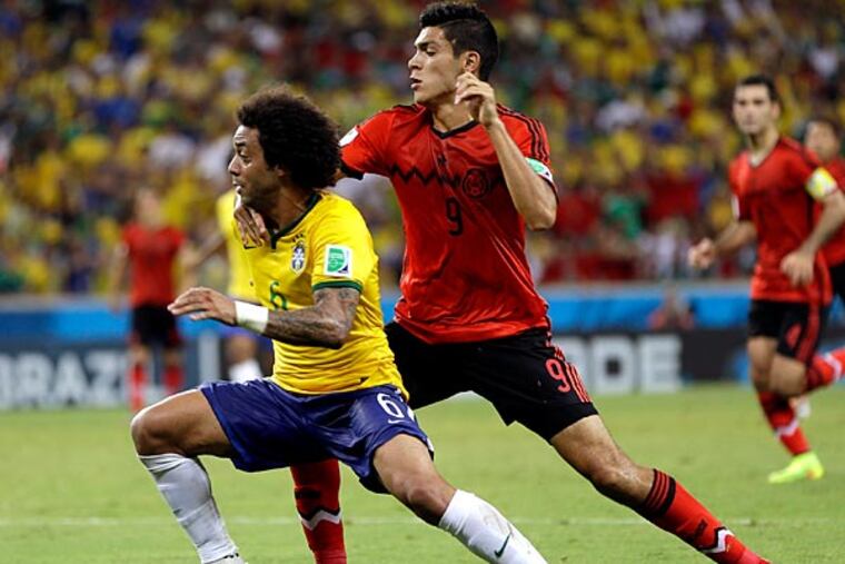 Mexico's Raul Jimenez, right, challenges Brazil's Marcelo during the group A World Cup soccer match between Brazil and Mexico at the Arena Castelao in Fortaleza, Brazil, Tuesday, June 17, 2014. (AP Photo/Andre Penner)