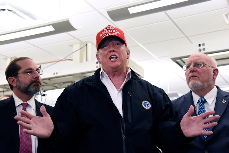 President Donald Trump speaks to members of the press as Health and Human Services Secretary Alex Azar, left, and CDC Director Robert Redfield, right, at the headquarters of the Centers for Disease Control and Prevention in Atlanta on Friday, March 6, 2020. (Hyosub Shin/Atlanta Journal-Constitution via AP)