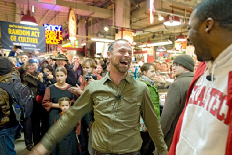 Turning to fellow baritone Norman Garrett, Troy Cook (center) lets out a hearty laugh at the end of the "flash opera" performed at noontime Saturday at Reading Terminal Market. (Clem Murray / Staff Photographer)