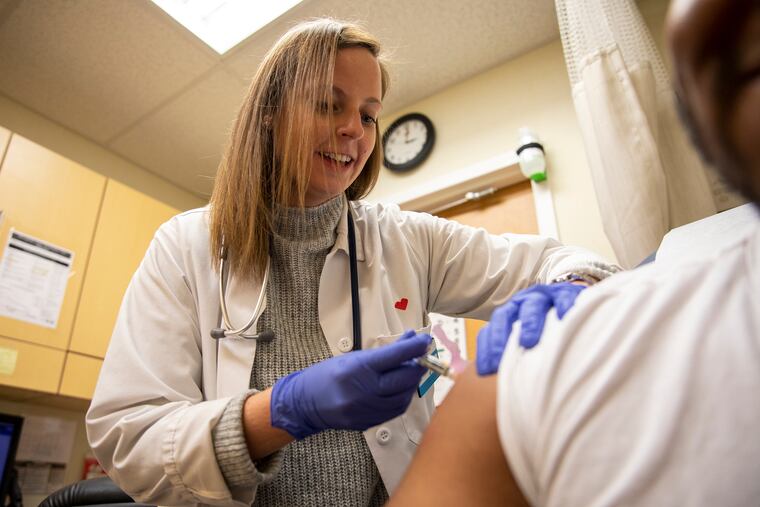 Kelly Moran, a nurse practitioner at MinuteClinic in the CVS at 15th and Spruce streets in Philadelphia, gives a flu shot to Jermaine Dabney, 20, of West Oak Lane. “I want everyone to get a flu shot so no one gets the flu,” Moran said.