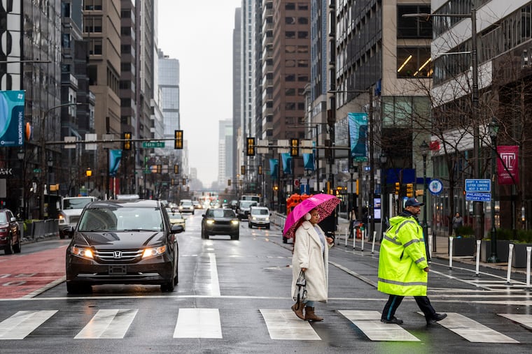 Taylor McCoy, 27, of Northeast Philadelphia, is on her way to the library during a rainy Saturday in Philadelphia. More wet stuff is in the forecast for New Year's Eve.
