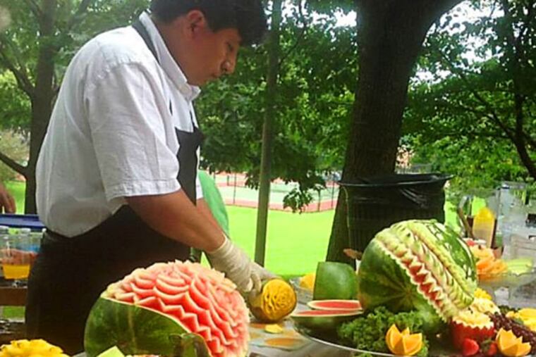 Roy Torres carves watermelons and other fruits at CARE Veggie Fest 2013.