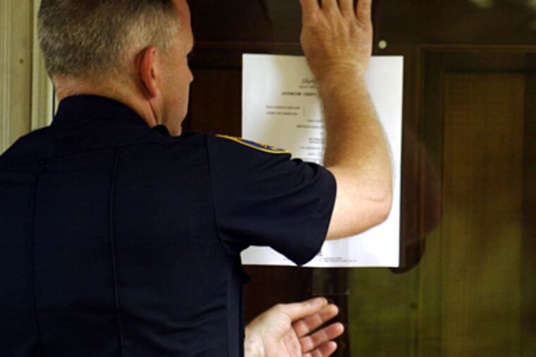 Lexington County Deputy Sheriff Jon Shokes tapes a foreclosure notice to a home in Lexington County, S.C. (AP Photo/Willis Glassgow)