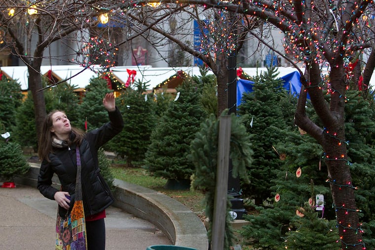 A woman stops to admire the lights as she walks through the Christmas Tree Stand at LOVE Park on Dec. 16, 2014. ( CHARLES FOX / Staff Photographer )