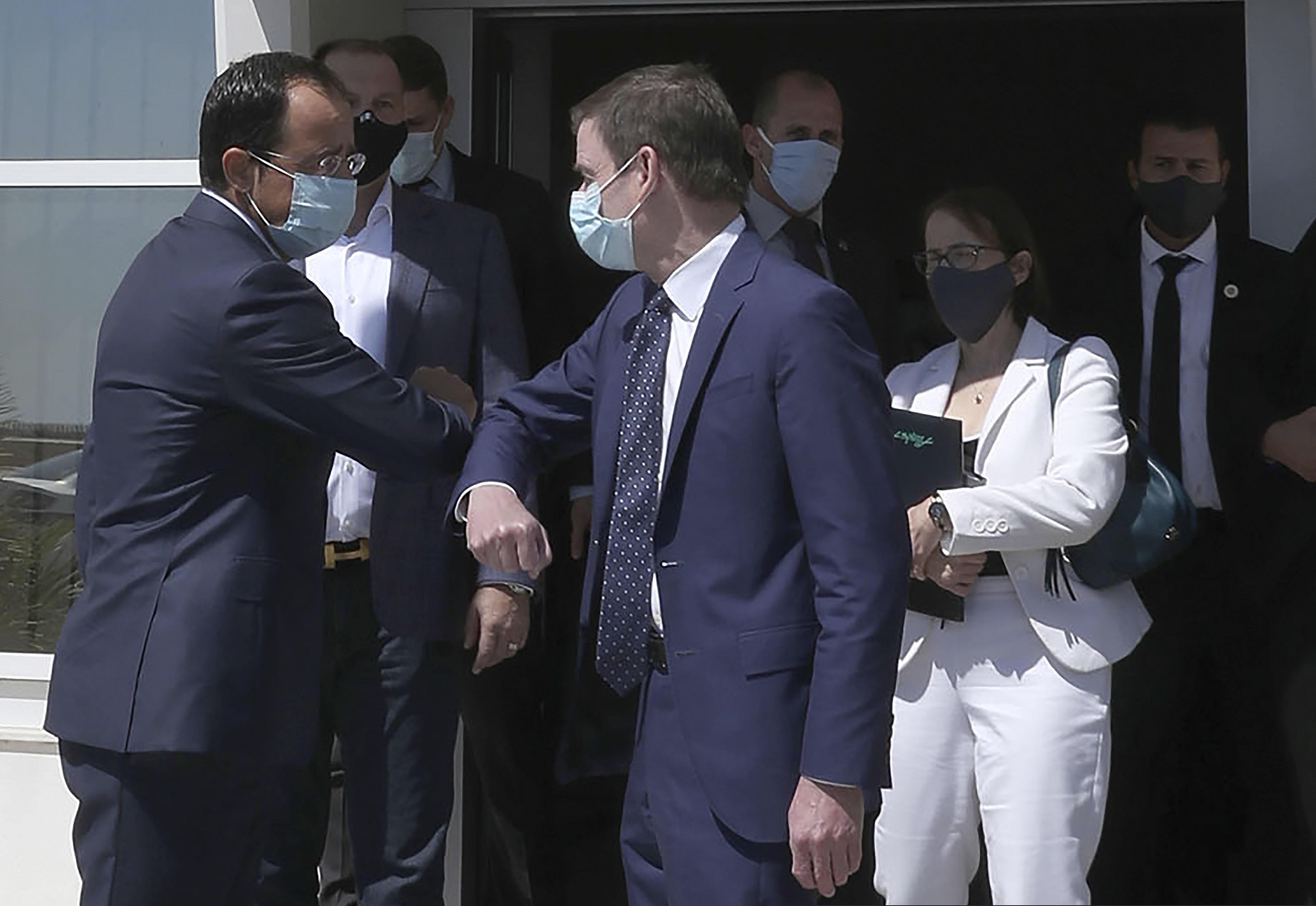 Cyprus' foreign minister Nikos Christodoulides, left, and Under Secretary of the United States of America, for Political Affairs, David Hale touch elbows following their meeting at Larnaca international airport, Cyprus, Sunday, Aug. 16, 2020. Hale's brief stop in Cyprus comes amid heightened tensions over Turkey's hydrocarbons search in waters Greece and Cyprus claim as their own.