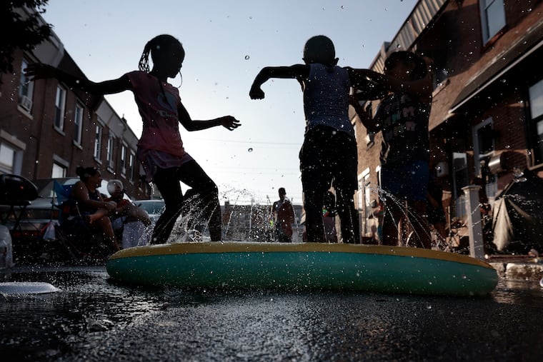 Makayla Byrd, 7, Hakim Sims, 7, and Gabby Mamrosch, 5, dance in a sprinkler on Thayer Street in the Harrowgate section of Philadelphia on Sept. 4.