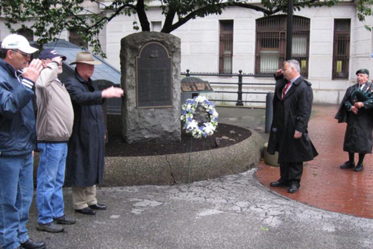At a ceremony honoring fallen city police officers, Philadelphia fire fighters salute after union president Bill Gault (second from right) placed a wreath near a memorial in City Hall courtyard. Dell Campbell played bagpipes during the morning remembrance on Sept. 11, 2009,