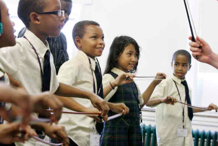 St. Francis de Sales students (from left) Sa'mya Moore, Jordan Jefferies, Craig Smith, Phonnica Narom, and Amir Nasr follow violin teacher Jose Sanchez.
