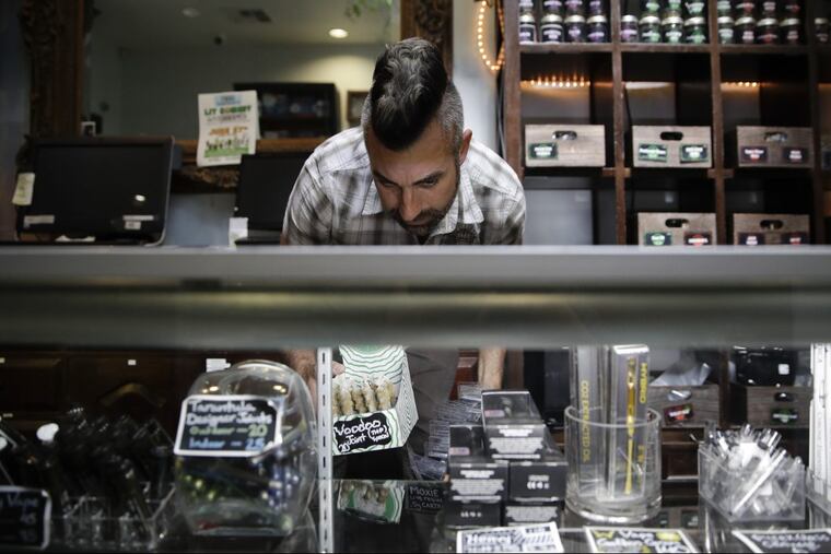 In this June 27, 2017, file photo, Jerred Kiloh, owner of the Higher Path medical marijuana dispensary, stocks shelves with with cannabis products in Los Angeles. The California treasurer is one of four counterparts seeking a meeting with U.S. Attorney General Jeff Sessions to resolve the industry’s legal problems.