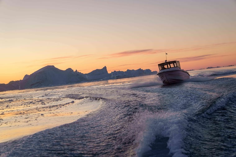 A fishing boat sails in front of an iceberg at Disko Bay near Ilulissat, Greenland, in January.