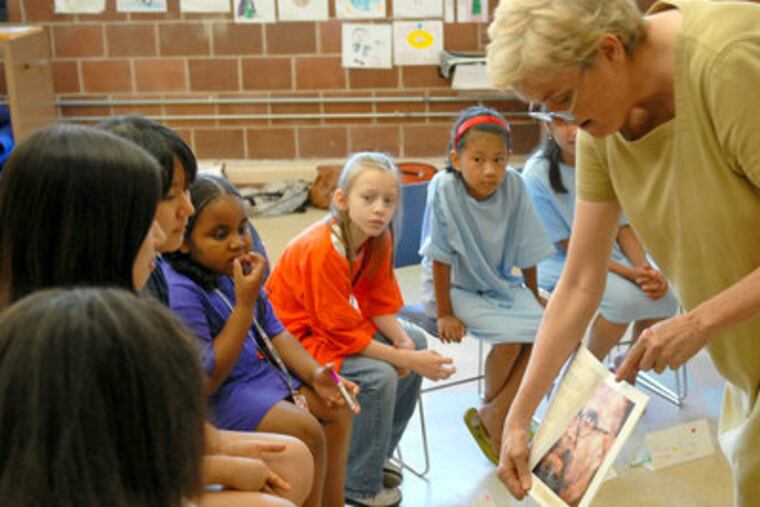 Anne Hagert shows book with examples of self portraits of artists during first meeting of the Girls Club. (Tom Gralish / Inquirer)