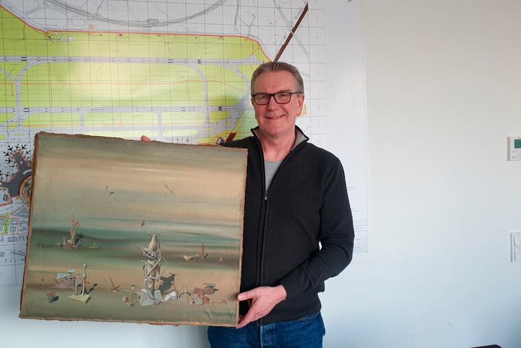 In this photo released by the police department in Duesseldorf, Chief Detective Michael Dietz holds a painting from French artist Yves Tanguy. A businessman, whose identity was not given, boarded a flight from Duesseldorf to Tel Aviv on Nov. 27, but forgot the painting by French surrealist Yves Tanguy, which was wrapped in cardboard, on the check-in counter. By the time he landed in Israel and contacted Duesseldorf police, the painting had disappeared but was later found at a nearby paper dumpster, according to police.(Polizei Duesseldorf via AP)