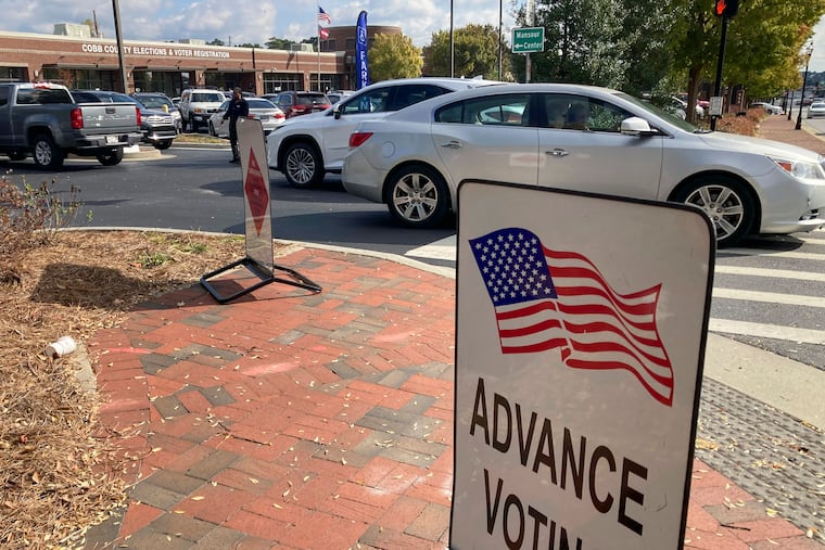 A sign showing the way for voters stands outside a Cobb County voting building during the first day of early voting, Monday, Oct. 17, 2022, in Marietta, Ga.