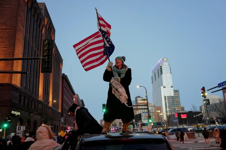 Teresa Hurst waves an upside-down American flag on top of a car during a rally against federal immigration enforcement in Minneapolis on Friday, Jan. 23.