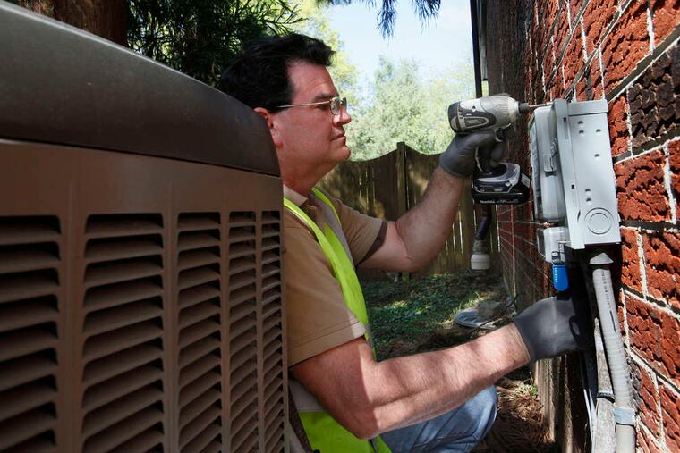 Michael P. King , a Peco field technician, installing a digital cycling unit near a house's central-air unit in 2012. MICHAEL S. WIRTZ / Staff Photographer