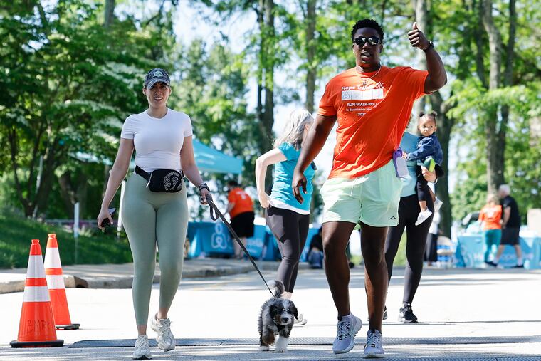 Eagles edge rusher KJ Henry with his girlfriend, Viviana Diaz, and their dog Rylo during the Hope Travels 5K Run-Walk-Roll fundraiser in Radnor on Sunday.
