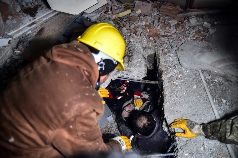 Emergency workers and medics rescue a woman out of the debris of a collapsed building in Elbistan, Kahramanmaras, in southern Turkey on Tuesday.
