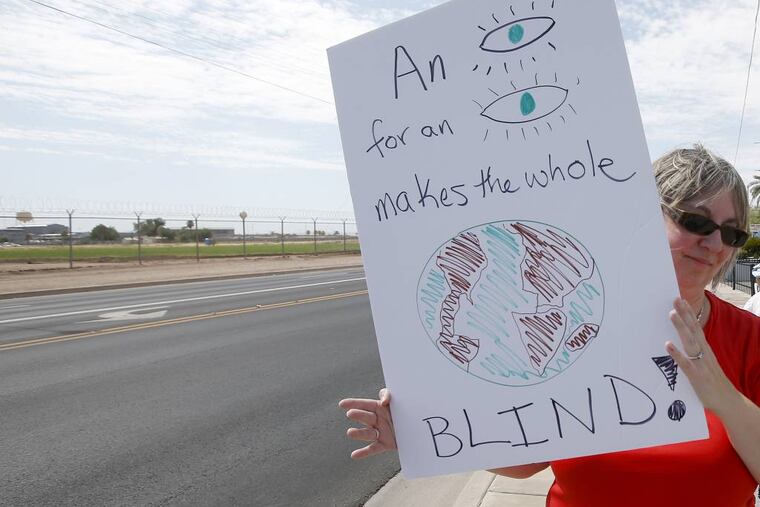 In this July 23, 2014, file photo, with the state prison in the background, Joan Bundy, of Casa Grande, Ariz., a death penalty opponent, protests the possible execution of Joseph Rudolph Wood in Florence, Ariz. In debate over slow executions, victim families wrestle with whether those condemned should suffer. (AP Photo/File)