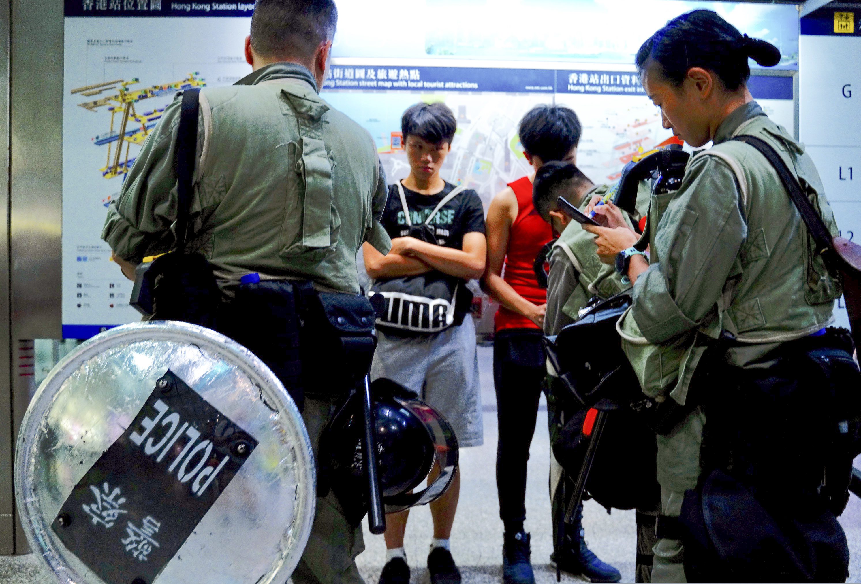 Riot police check passengers' bags at airport express central station in downtown Hong Kong, Saturday, Sept. 7, 2019. Hong Kong authorities were limiting airport transport services and controlling access to terminals Saturday as they braced for a second weekend of disruption following overnight demonstrations that turned violent.