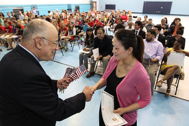 Julio Feldman, a naturalized citizen and the principal of Marlton Elementrary School, left, hands an American flag to Yan Yun Cheng, right, after she was presented her certificate of citizenship at Marlton Elementrary School on Monday, June 9, 2014. ( Michael Bryant / Staff Photographer )